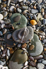 Various size and shape color pebble stones lying one on another with white straight streak line combined of three stones