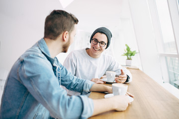 Men are sitting in front of the table near window