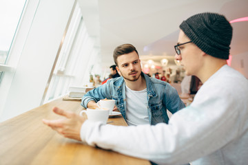 Men are sitting in front of the table near window