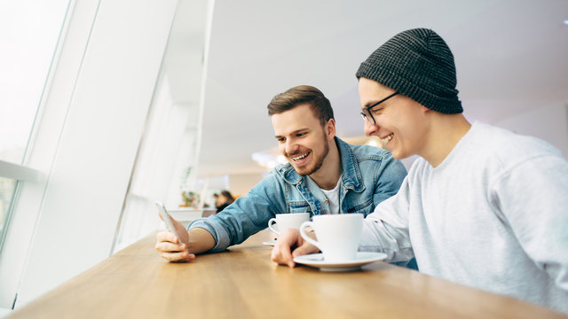 Men are sitting in front of the table near window