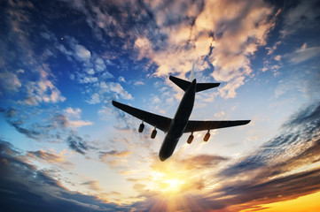Fototapeta premium Airplane in sunset sky. Airplane travel composition.