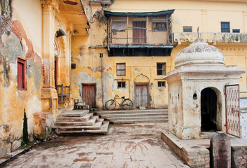 Fototapeta na wymiar Old bycicle stands in the courtyard of poor historical indian house