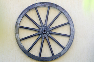 wooden old antique historic wheel used for carriage of stagecoaches hanging against a white wall background zoom on full frame