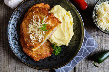 Fried pork cutlets coated in potato batter, studded with cheese and served with mashed potato