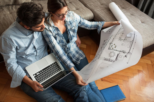 Young couple examining blueprints of they new house.Moving house concept.
