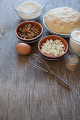 Turkish pasties pogaca ingredients on the grey wooden table: ready dough, flour, yogurt, feta cheese with herbs and mince; yeast and whisk; selective focus on the dough