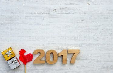 Red rooster, symbol of 2017 on the Chinese calendar. Lollipop in the form of a red rooster on a white wooden background