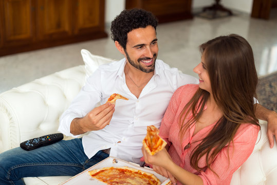 Couple Watching Tv And Eating Pizza