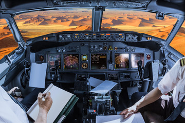 Airplane cockpit flying on Dead Valley, Sossusvlei desert in Namib Naukluft National Park, Namibia, with pilots arms and blank white papers for copy space.