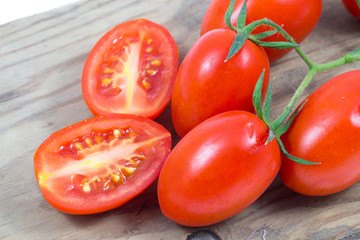 fresh, ripe tomatoes on wood background / red tomato with slice on wooden surface.