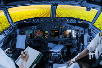Airplane cockpit flying on Napa Valley at sunset, California, United States, with pilots arms and blank white papers for copy space.