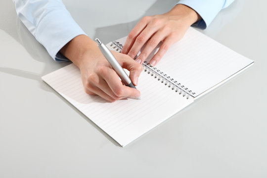 female hands with pen writing on notebook