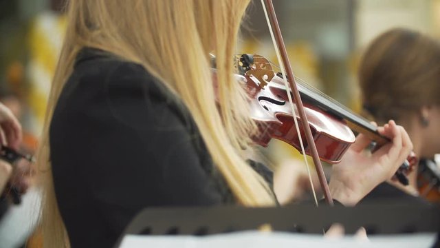 beautiful girl playing the violin with orchestra.