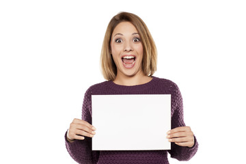 happy young woman holding a blank sheet of paper for advertising