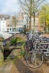 Row of bicycles standing next to canal in Amsterdam at spring, Netherlands