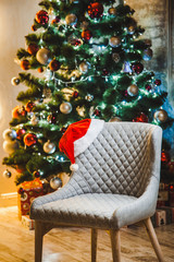 Beautiful New year room with a Christmas tree and a chair with a Santa hat