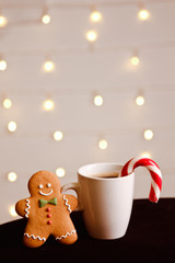 Gingerbread man with candy standing at cup of coffee on a blurred background. Christmas card