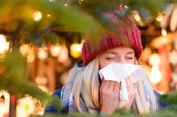 Young woman outdoors at night blowing her nose