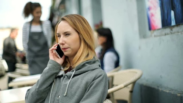 Girl sitting outdoors at cold day and calling to someone
