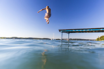Junge springt vom Steg in den See