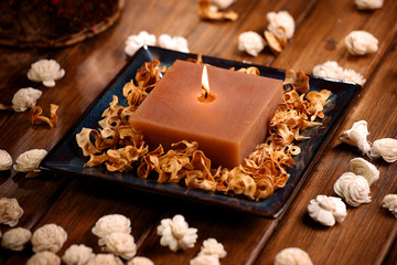 Candle with cream flowers on wodden table