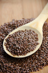 A spoonful of flax seed set on a wooden surface