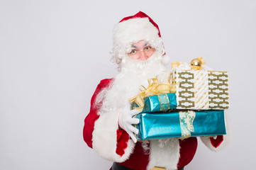 Santa holding many Christmas gifts