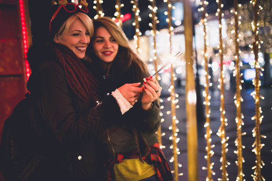Beautiful young women enjoying Christmas or New Year night on a city street. 