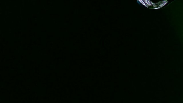 Single drop fall in a black background in slow motion