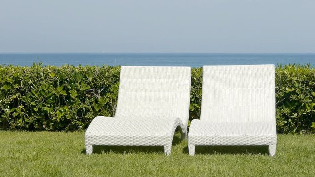 Two empty white sun loungers on grass