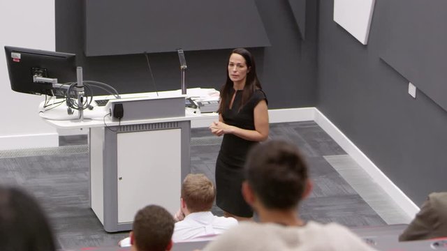 Back row student POV of female teacher in lecture theatre, shot on R3D