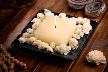 Aromatic rustic candle with white sola flowers on wodden table