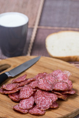 Sliced sausages on the wooden board with bread