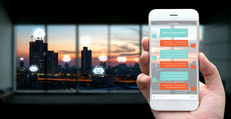 Chat bot , Robo everywhere and future marketing concept. Human hand holding white phone , application ui and robot icons with city sunset background