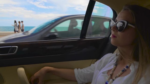 Attractive woman in sunglasses riding in taxi along embankment, enjoying view