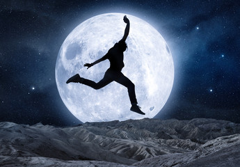 silhouette of a man jumping in front of full moon