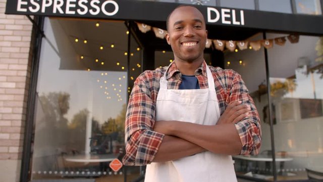 Black male owner walks into focal plane outside coffee shop