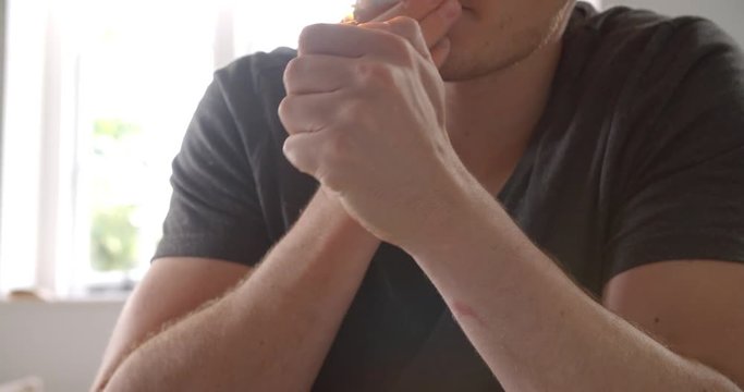 Slow Motion Of Young Man Lighting Joint At Home