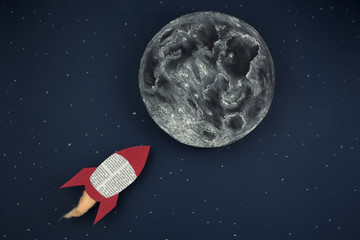 Cohete espacial hecho con papel de periódico dirigiéndose a la Luna por el espacio exterior. © josemanuelerre