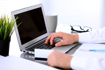 Close up of business woman hands using credit card and laptop computer