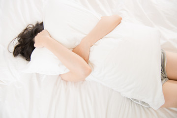 beautiful asian woman feel unwell painful and holding pillow