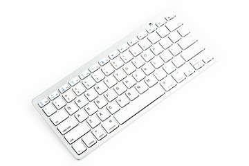 Modern aluminum computer keyboard. Wireless, blue-tooth computer keyboard isolated on white background. Close up of whit, silver  wireless aluminum fingerboard with english letters.Top, side view.