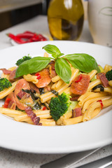 A delicious fresh gourmet Italian strozzapreti pasta dish, with pancetta, italian sausage, broccoli, vegetables, topped with fresh basil.