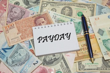Notebook page with text PAYDAY, background from different world Currencie