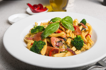 A delicious fresh gourmet Italian strozzapreti pasta dish, with pancetta, italian sausage, broccoli, vegetables, topped with fresh basil.