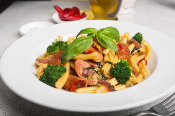 A delicious fresh gourmet Italian strozzapreti pasta dish, with pancetta, italian sausage, broccoli, vegetables, topped with fresh basil.