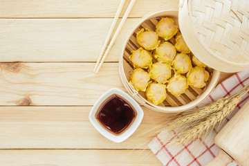 Steamed dumplings (chinese dim sum) in bamboo basket, serve with chopsticks and napkin on wooden...