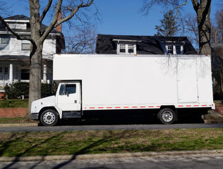 White moving van parked on neighborhood street. Early spring. Blue sky. Horizontal.