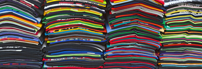 Stacked rows of colorful souvenir t-shirts. Horizontal.