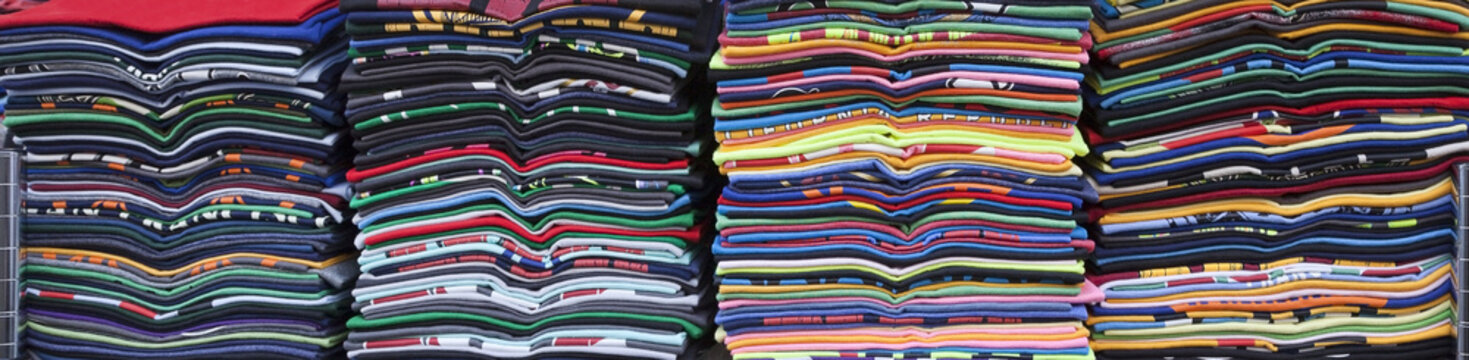 Stacked rows of colorful souvenir t-shirts. Horizontal.